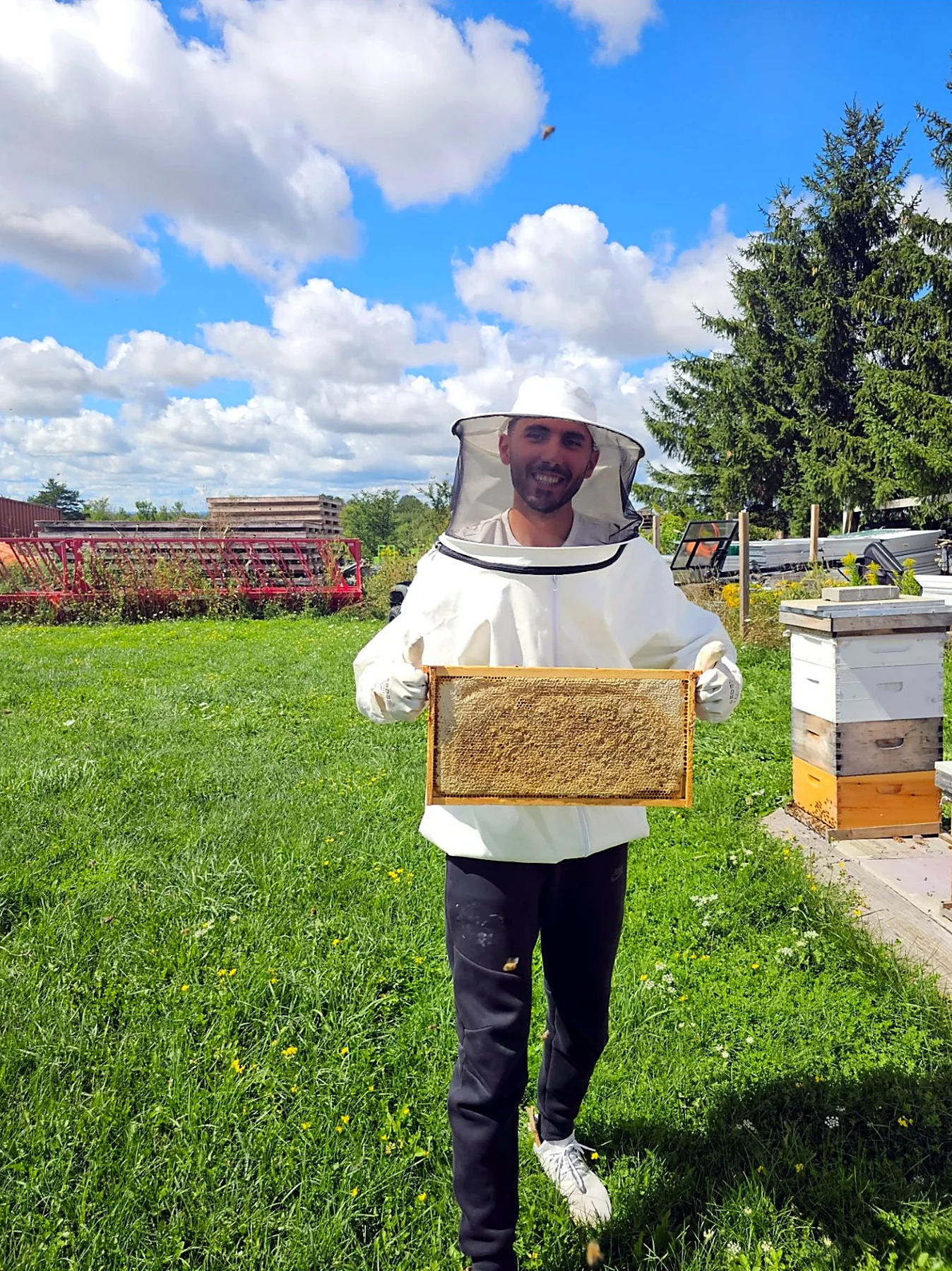 Cem, the beekeeper's son, holding a comb frame in the field